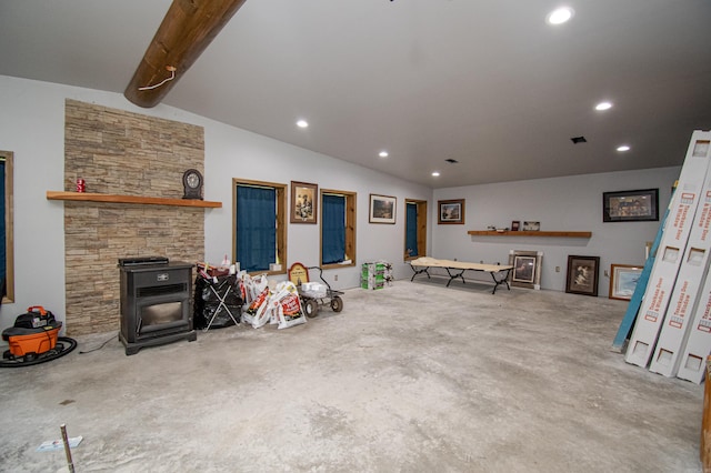 unfurnished living room with a stone fireplace, concrete flooring, and a wood stove