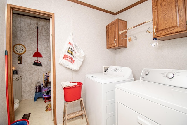 laundry area featuring cabinets, crown molding, and washing machine and clothes dryer