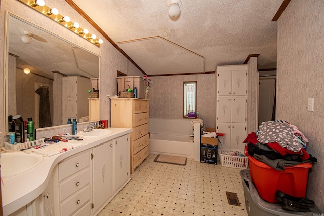 bathroom featuring a washtub, vanity, a textured ceiling, and ornamental molding