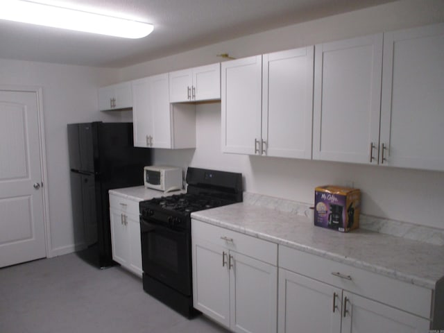 kitchen with black appliances, white cabinets, and light stone countertops