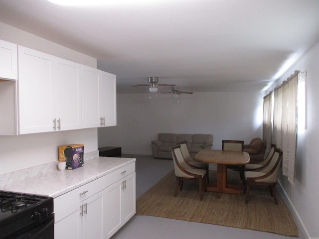 kitchen with white cabinets, ceiling fan, and black range oven