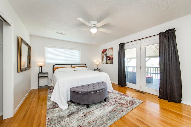 bedroom with ceiling fan, french doors, access to outside, light hardwood / wood-style floors, and a textured ceiling