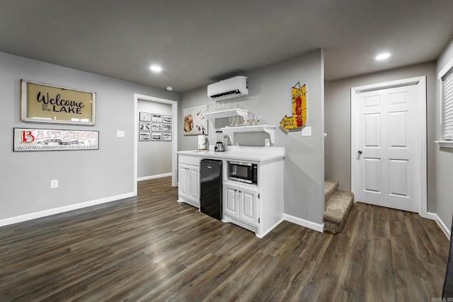 kitchen featuring white cabinets, dark hardwood / wood-style floors, stainless steel microwave, and a wall mounted air conditioner