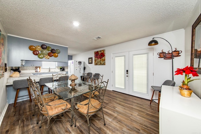 dining space with dark hardwood / wood-style floors, sink, french doors, and a textured ceiling