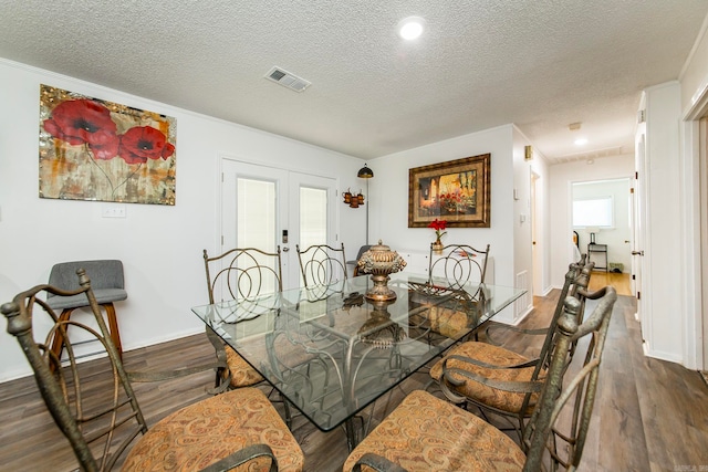 dining space featuring a textured ceiling, hardwood / wood-style flooring, and french doors