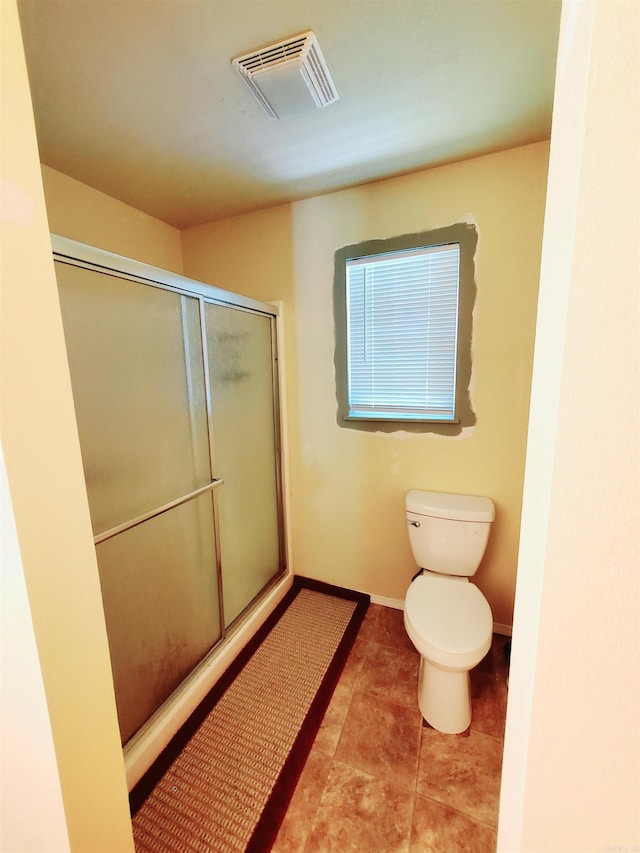 bathroom featuring toilet, visible vents, baseboards, tile patterned floors, and an enclosed shower