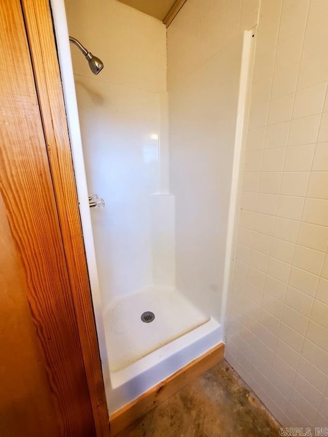 full bath with a shower stall and unfinished concrete flooring