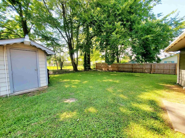 view of yard with an outbuilding, a storage unit, and fence