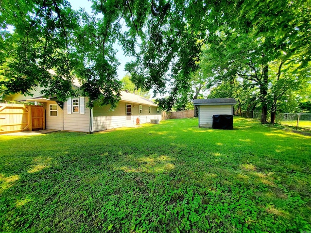 view of yard with an outbuilding, a fenced backyard, and a storage shed