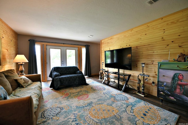 living room with wood finished floors, french doors, visible vents, and wood walls