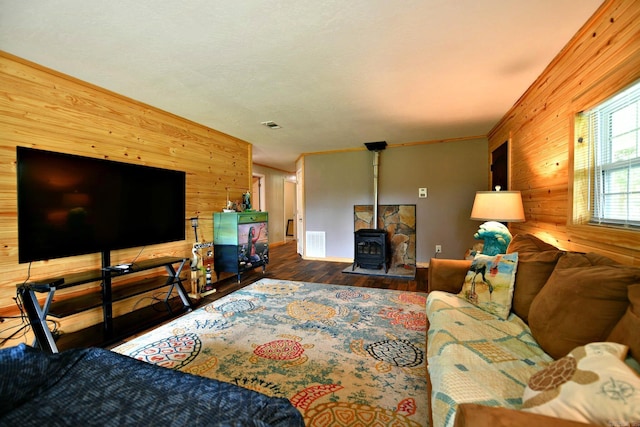 living room with visible vents, wood finished floors, wood walls, and a wood stove