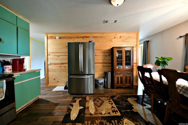 kitchen featuring wooden walls, visible vents, green cabinetry, dark wood finished floors, and stainless steel appliances