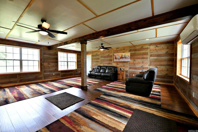 living area with wood-type flooring, wood walls, a ceiling fan, and a wall mounted AC