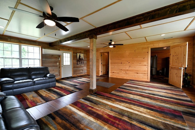 living room featuring wooden walls, wood finished floors, and a ceiling fan