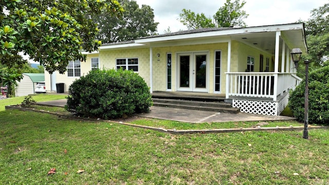 back of property featuring french doors, a yard, and concrete block siding