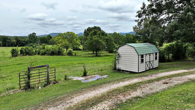 view of outbuilding featuring a mountain view, an outdoor structure, and fence