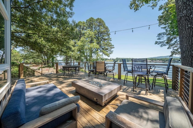 wooden terrace with a water view and a fire pit