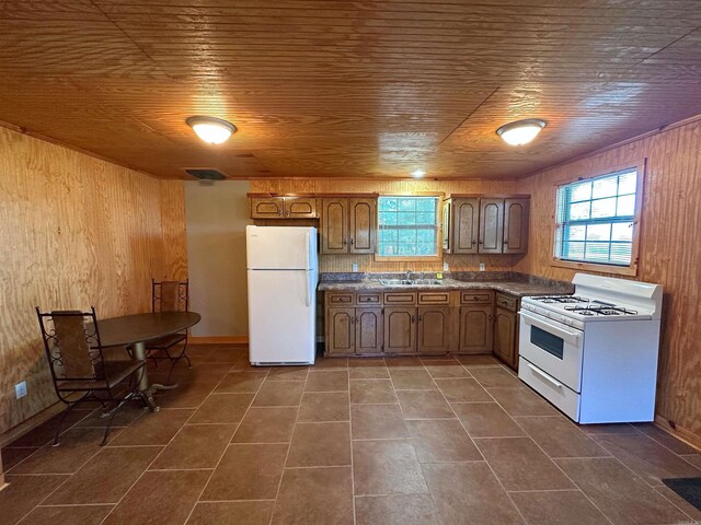 kitchen with sink, white appliances, wooden walls, and wood ceiling