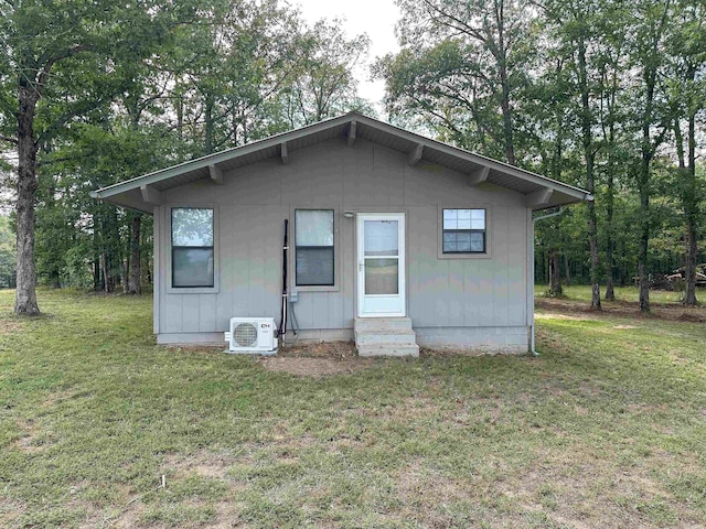 back of property with ac unit and a yard