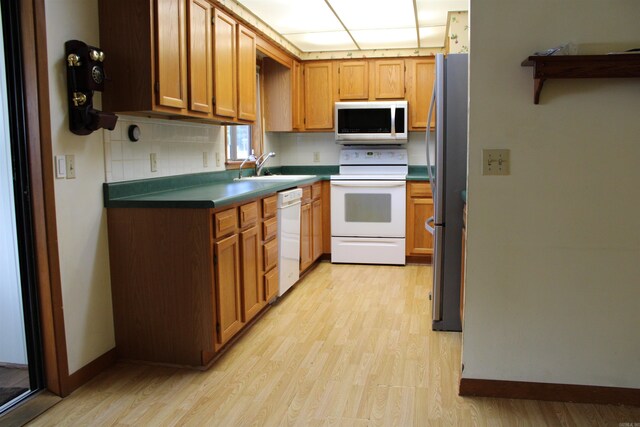 kitchen with backsplash, appliances with stainless steel finishes, sink, and light wood-type flooring