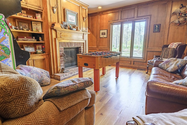 living room with a brick fireplace, wood walls, and hardwood / wood-style floors