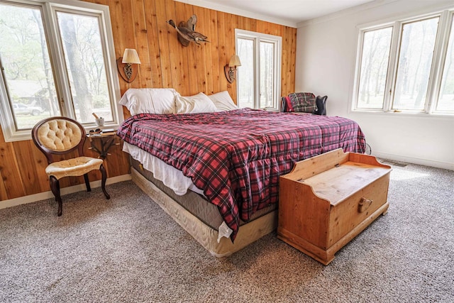 bedroom with wooden walls, multiple windows, and carpet floors