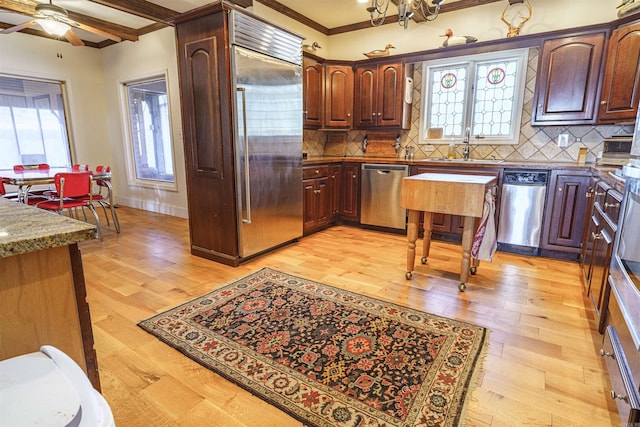 kitchen featuring ceiling fan, light hardwood / wood-style flooring, backsplash, ornamental molding, and appliances with stainless steel finishes