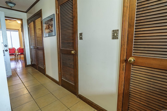 corridor with tile floors and crown molding