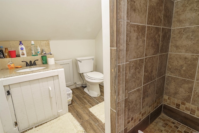 bathroom featuring tiled shower, vaulted ceiling, vanity, and toilet