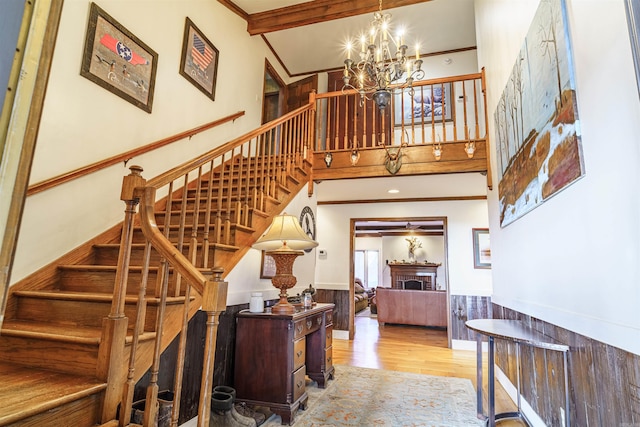 stairs with wood-type flooring, a towering ceiling, and an inviting chandelier