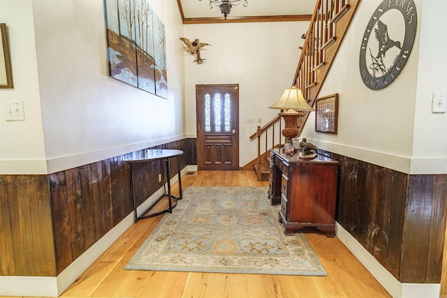 foyer entrance with light hardwood / wood-style flooring and crown molding