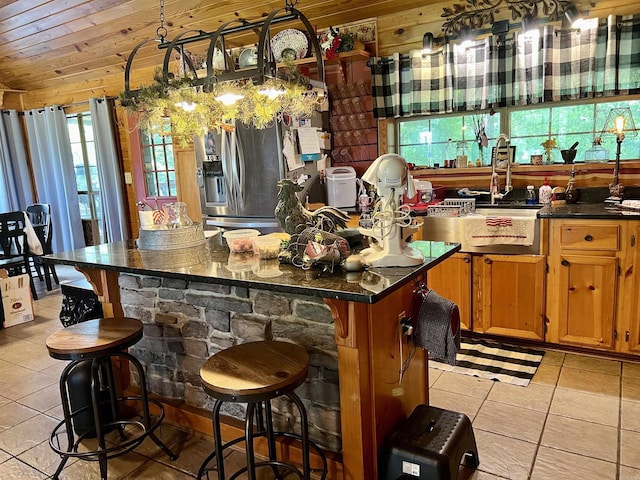 bar featuring stainless steel fridge with ice dispenser, light tile patterned floors, wooden ceiling, and sink