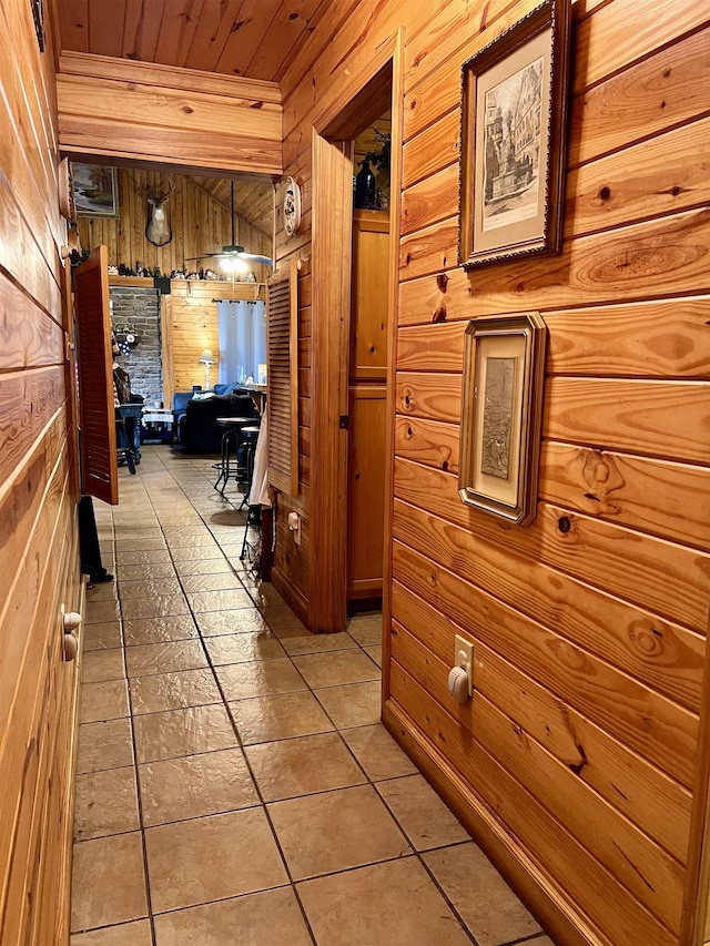 corridor featuring wood ceiling, light tile patterned flooring, and wood walls