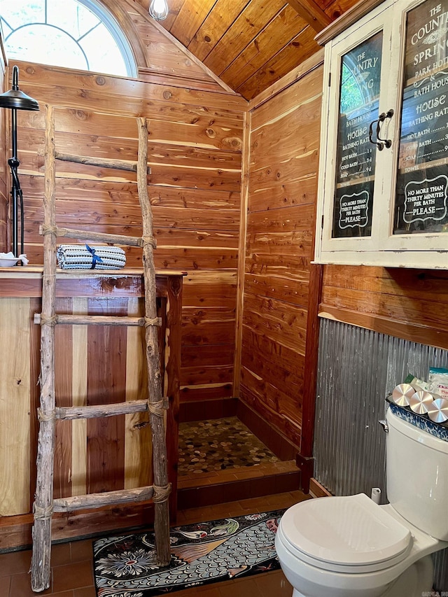 bathroom with lofted ceiling, toilet, wood ceiling, wooden walls, and tile patterned flooring