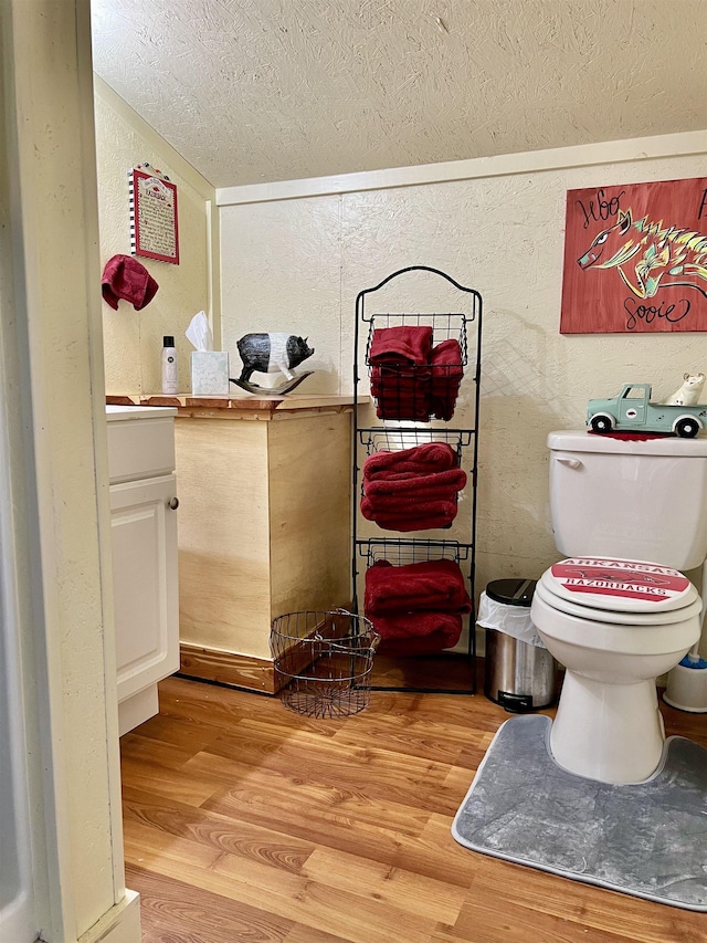 bathroom featuring vanity, hardwood / wood-style flooring, a textured ceiling, and toilet