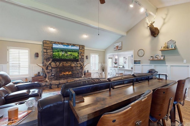 living room featuring hardwood / wood-style floors, lofted ceiling with beams, a healthy amount of sunlight, and a stone fireplace