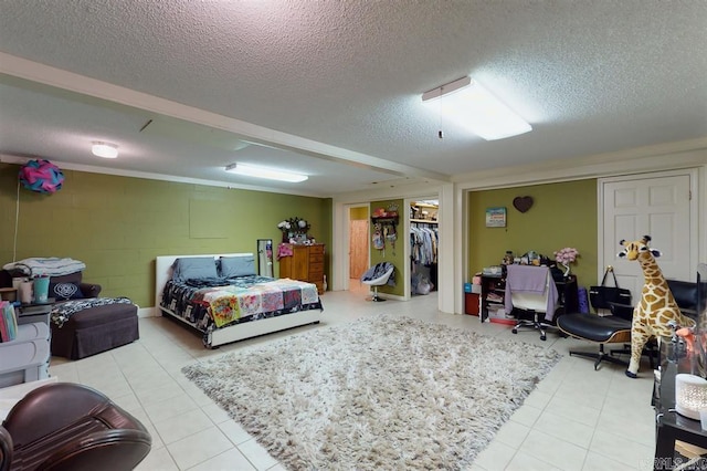 tiled bedroom featuring a textured ceiling, a walk in closet, and a closet