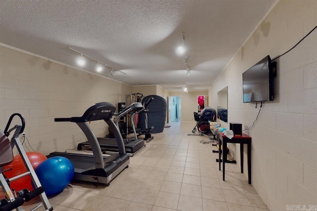 workout room with a textured ceiling, light tile patterned floors, and rail lighting