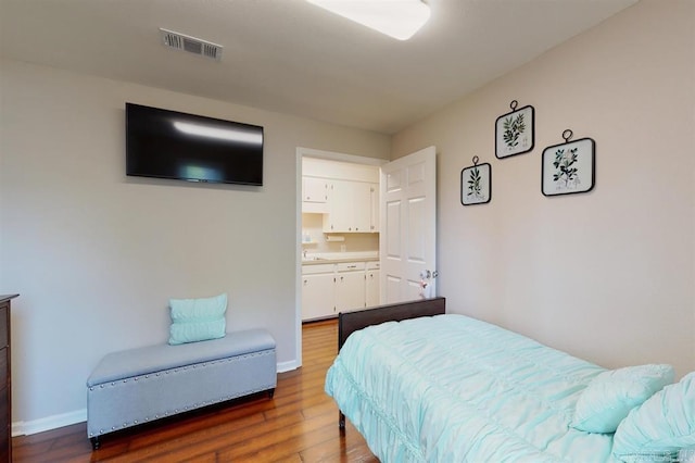 bedroom with dark hardwood / wood-style flooring and connected bathroom