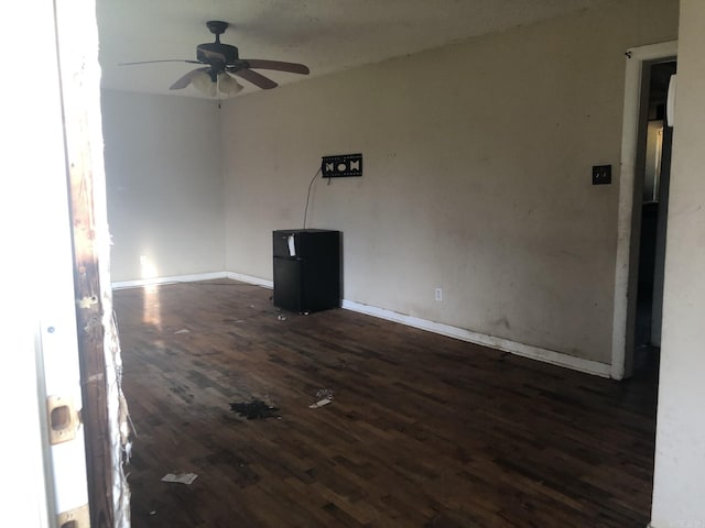 unfurnished room featuring dark wood-type flooring and ceiling fan