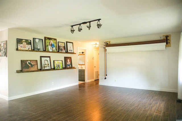 unfurnished living room with dark wood-type flooring, a barn door, and track lighting