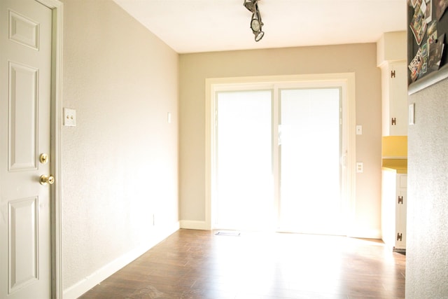 spare room with dark hardwood / wood-style flooring and rail lighting