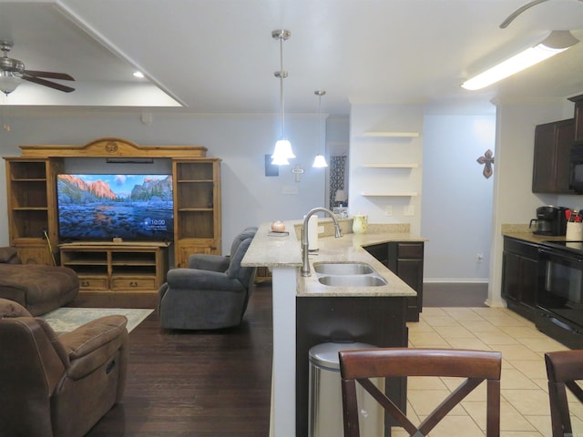 kitchen featuring kitchen peninsula, black appliances, sink, hanging light fixtures, and a breakfast bar area