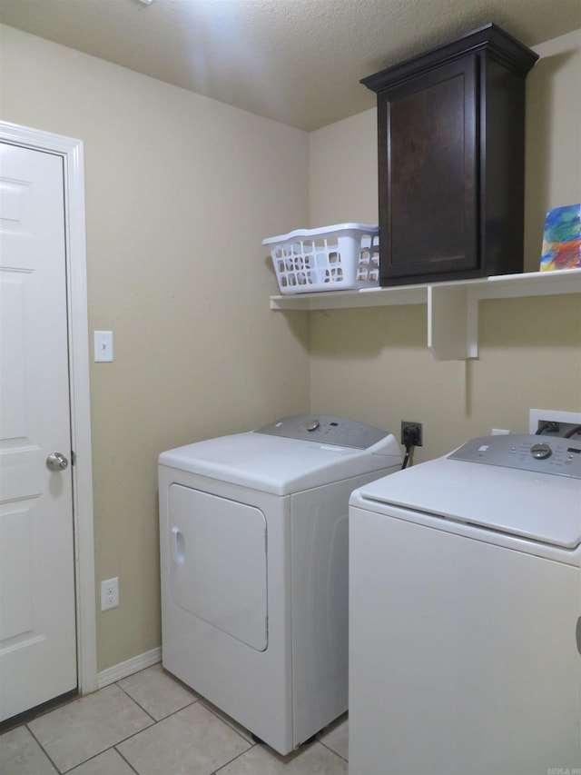 washroom featuring cabinets, washing machine and dryer, and light tile patterned flooring