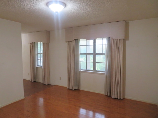 unfurnished room with wood-type flooring, plenty of natural light, and a textured ceiling