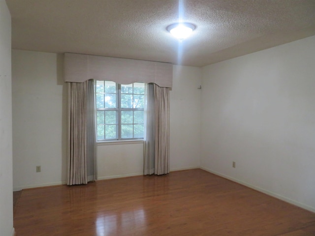 spare room featuring hardwood / wood-style flooring and a textured ceiling