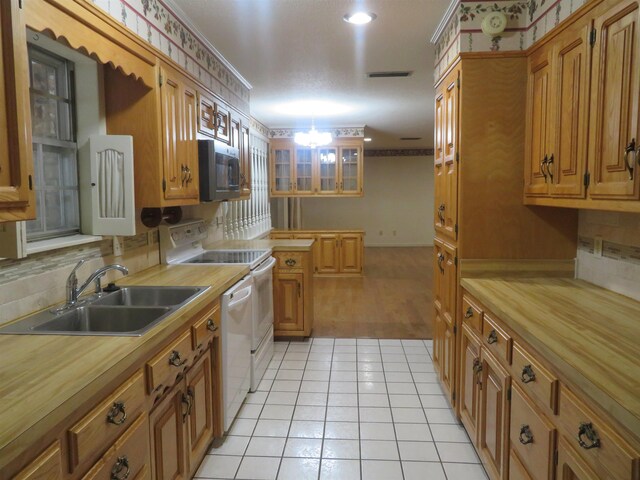 kitchen featuring light tile patterned flooring, sink, decorative backsplash, ornamental molding, and electric range