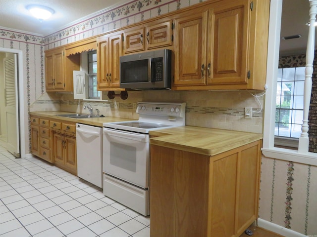 kitchen featuring tasteful backsplash, light tile patterned flooring, sink, and white appliances