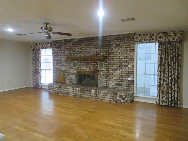 unfurnished living room featuring hardwood / wood-style floors, a fireplace, ornamental molding, and ceiling fan