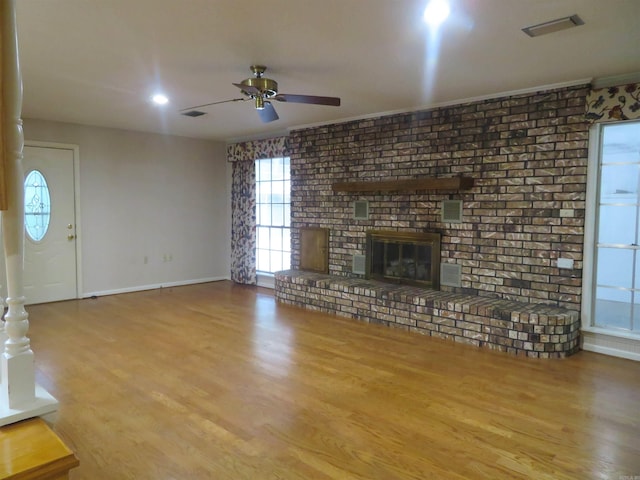 unfurnished living room with brick wall, a brick fireplace, hardwood / wood-style floors, and ceiling fan